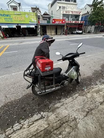 Nhân viên chở ắc quy Enimac bằng xe máy trên quốc lộ